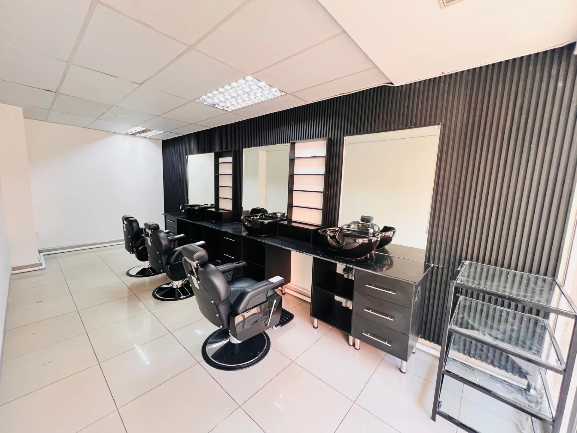 The Velvet Edge barbershop — black barber chairs and illuminated stations